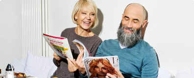 Zwei Personen, die nebeneinander sitzen und Zeitschriften lesen.